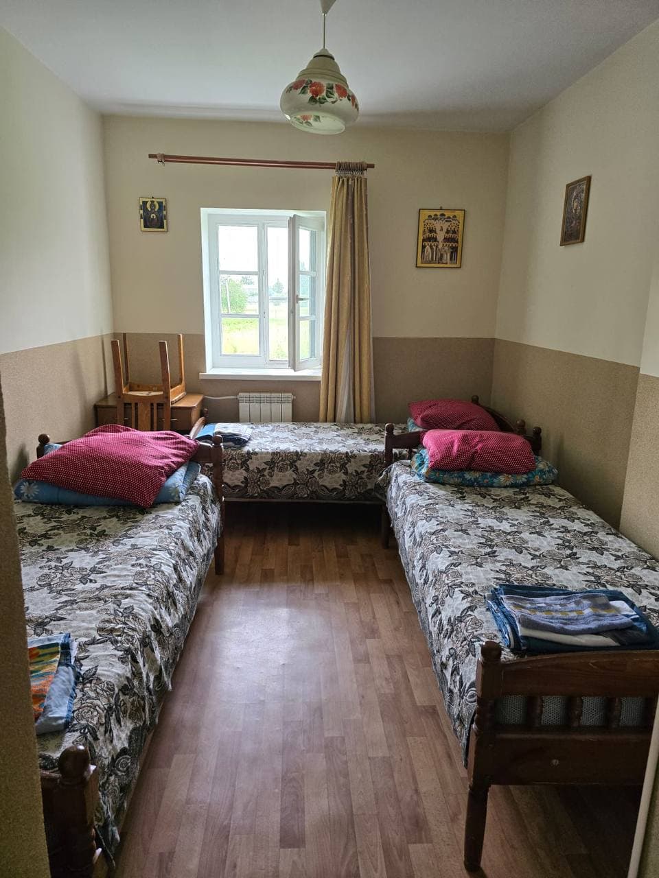 Трёхместная комната: три кровати, окно и иконы на стенах